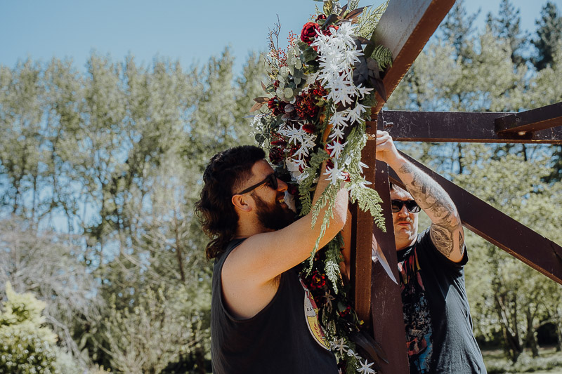 Groomsmen adjusting the flowers for the ceremony arch